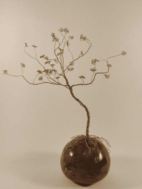 Arbre de vie en fil de fer doré posé sur une boule en céramique émaillée en marron avec des effets de taches noires et vertes
