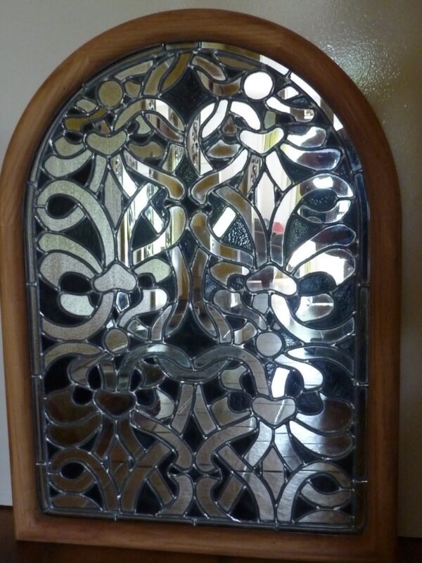 vitrail représentant des arabesques médiévales. Il est réalisé dans un cadre en bois avec du verre noir et du miroir