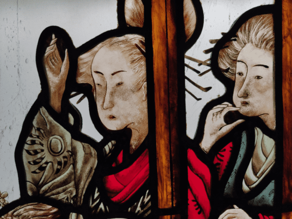vitrail inséré dans une boite lumineuse représentant deux Geishas derrière une fenêtre en bois. Elles observent quelque chose au loin. Le vitrail s'intitule "le retour"
