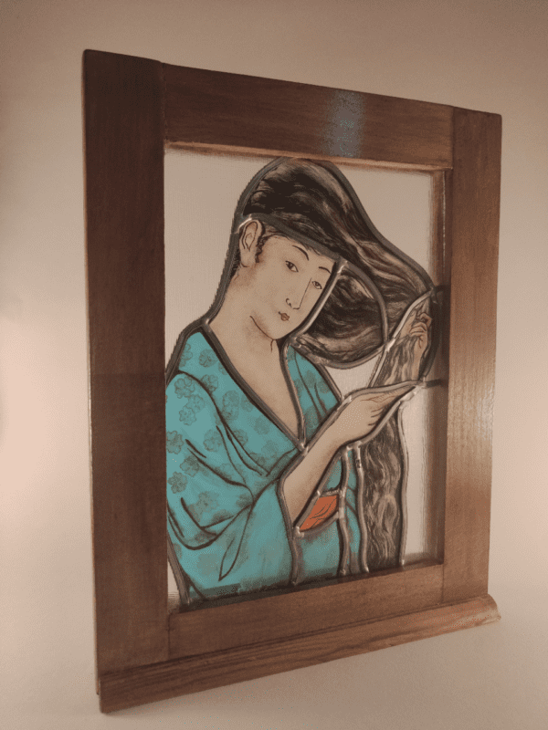 Vitrail Litya représentant une Geisha avec un peignoir bleu qui se coiffe. Il est inséré dans un cadre en bois