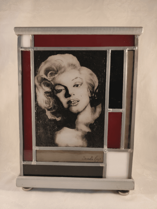 Lampe vitrail Marilyne (portrait de Marilyne Monroe) avec un encadrement de verres rouges et noirs. Vue de face. Lampe éteinte
