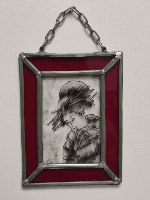 petit médaillon mini Shan avec une chainette d'accroche représentant un portrait de Geisha peint à l'émail noir avec un liseré de couleur rouge