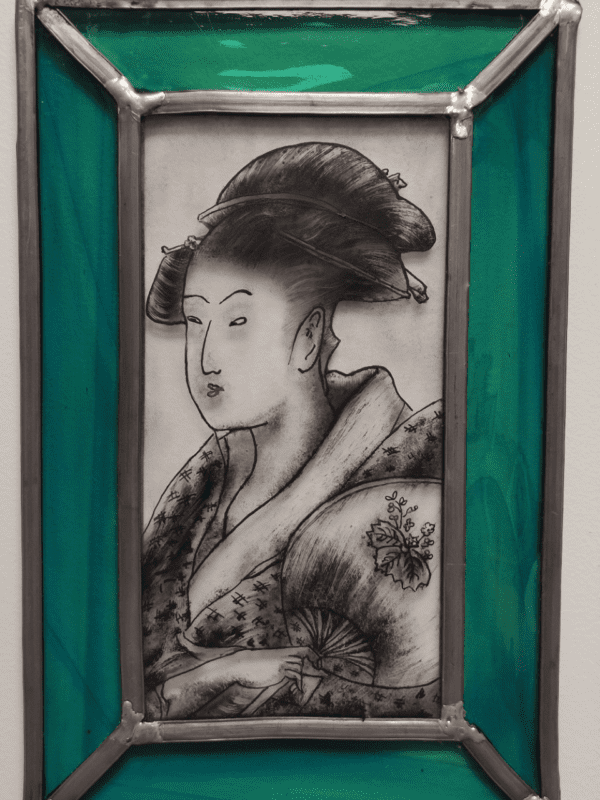 Médaillon Poldyne de forme rectangulaire. Il représente un portrait de geisha peint à la grisaille noire. Les bord sont bleu turquoise