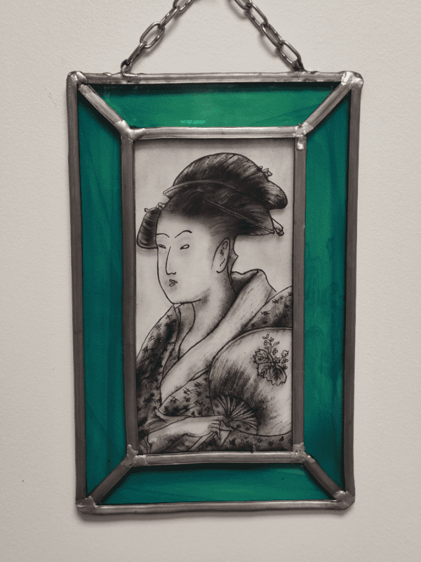 Médaillon Poldyne de forme rectangulaire avec une chainette d'accroche. Il représente un portrait de geisha peint à la grisaille noire. Les bord sont bleu turquoise
