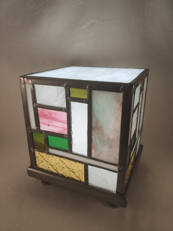 lampe Tyni en vitrail allumée en forme de cube d'inspiration Mondrian en jaune, vert et rose. elle est présentée de trois quart