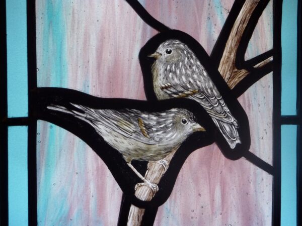 vitrail de deux petits oiseaux sur une branche avec un liseré de verres bleus. Il est inséré dans une boite en bois avec un système d'éclairage