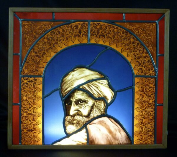 Vitrail d'un portrait oriental. Ce vitrail est inséré dans une boite en bois avec un système d'éclairage. Il représente le portrait d'un homme barbu âgé avec un turban sur la tête. Il est entouré d'une arabesque mauresque